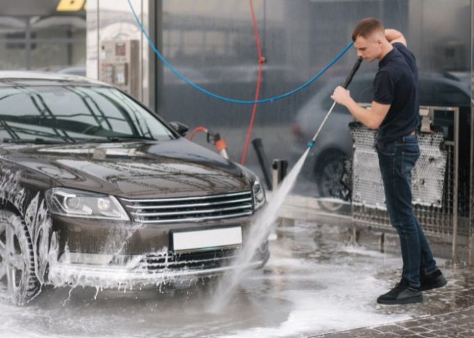 Mężczyzna na myjni bezdotykowej myje samochód aktywną pianą