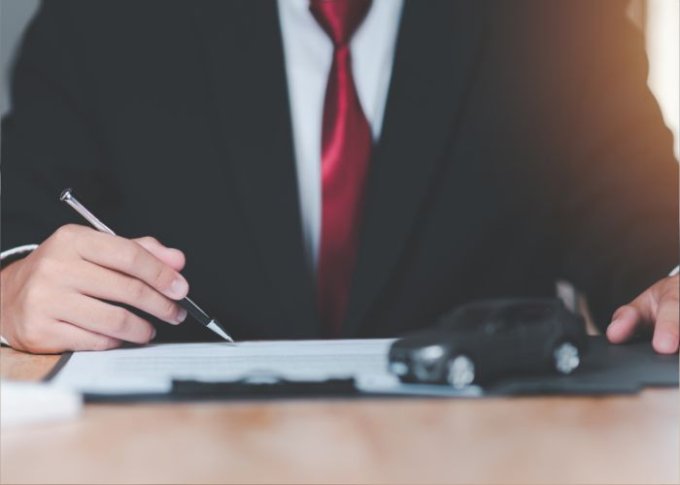 Mężczyzna podpisuje dokumenty potrzebne do leasingu samochodowego na firmę